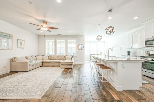408 Grant Ave W, Madera, CA 93636 - kitchen with appliances with stainless steel finishes, a sink, a breakfast bar area, white cabinetry, and dark wood-style floors