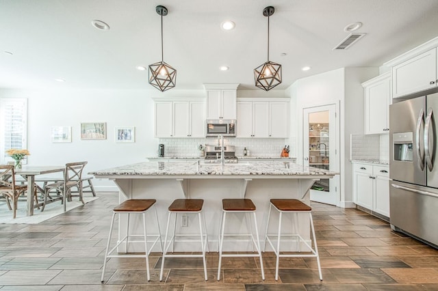 408 Grant Ave W, Madera, CA 93636 - kitchen with a kitchen breakfast bar, backsplash, visible vents, stainless steel appliances, and recessed lighting