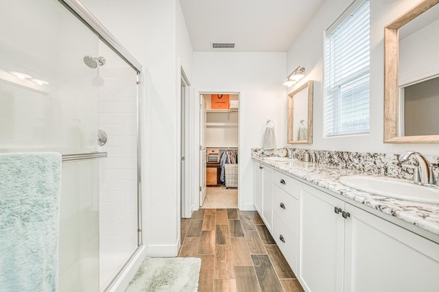 408 Grant Ave W, Madera, CA 93636 - full bathroom with visible vents, wood tiled floor, a walk in closet, a sink, and a stall shower