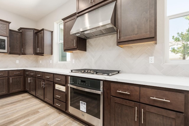 256 Huckleberry Ln S, Madera, CA 93636 - kitchen with dark brown cabinets, light countertops, under cabinet range hood, tasteful backsplash, and appliances with stainless steel finishes
