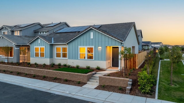 276 Huckleberry Ln S, Madera, CA 93636 - view of front of home featuring roof mounted solar panels, fence, and board and batten siding