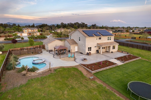 3887 N Condor Ct, Sanger, CA 93657 - rear view of house with a fire pit, a patio, roof mounted solar panels, a fenced backyard, and stucco siding