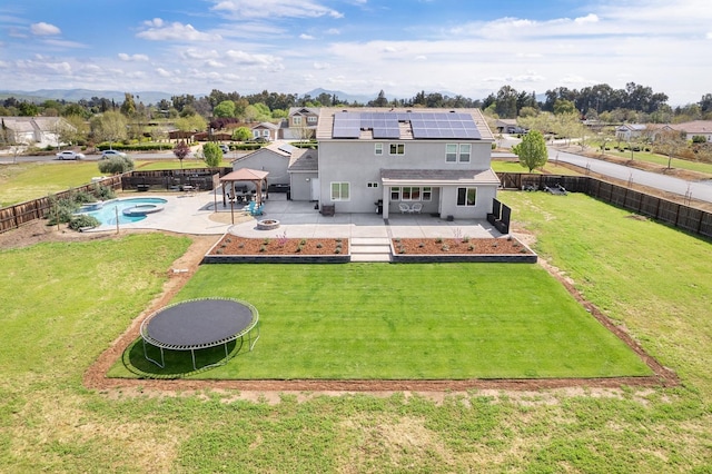 3887 N Condor Ct, Sanger, CA 93657 - rear view of property with a patio, roof mounted solar panels, a fenced backyard, stucco siding, and a trampoline