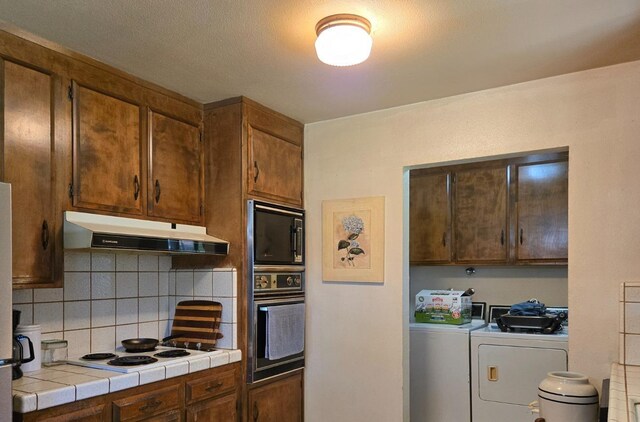26174 Haley Way, Madera, CA 93638 - kitchen featuring oven, under cabinet range hood, tile counters, independent washer and dryer, and backsplash