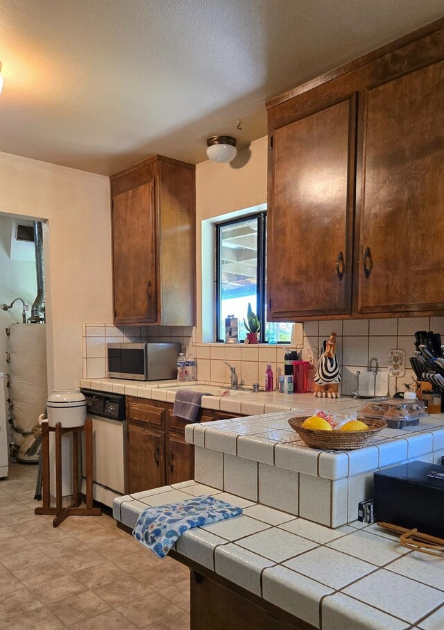 26174 Haley Way, Madera, CA 93638 - kitchen with stainless steel microwave, a sink, white dishwasher, tile counters, and backsplash