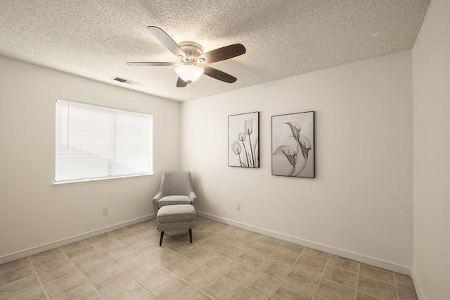 sitting room with baseboards, visible vents, a textured ceiling, and a ceiling fan