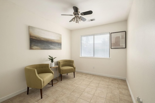 living area featuring baseboards, light tile patterned flooring, visible vents, and a ceiling fan