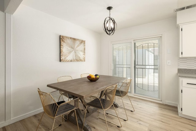 dining space with baseboards, visible vents, light wood-style floors, and a chandelier