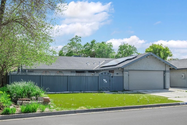 view of front of house with a gate, roof mounted solar panels, a garage, a fenced front yard, and driveway