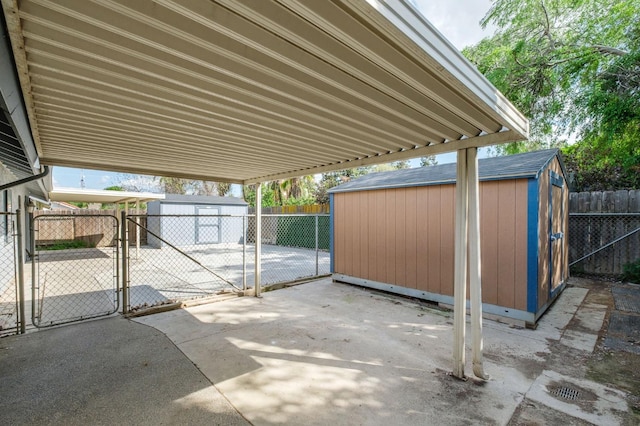 view of patio featuring an outbuilding, a fenced backyard, a gate, and a storage unit