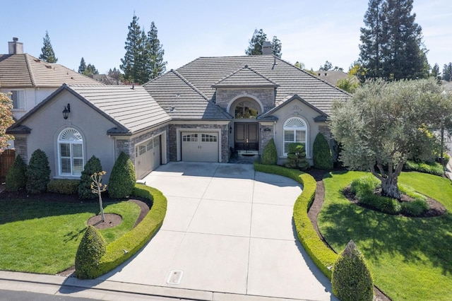 1643 E Shadow Glen Dr, Fresno, CA 93730 - french country home featuring a front yard, an attached garage, driveway, and stone siding