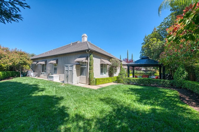 1643 E Shadow Glen Dr, Fresno, CA 93730 - rear view of house featuring a lawn, a gazebo, a chimney, and stucco siding