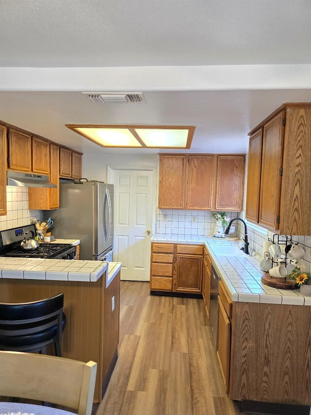 1295 E Athens Ave, Fresno, CA 93720 - kitchen with tile counters, under cabinet range hood, and brown cabinets