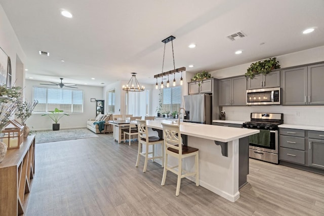 kitchen featuring stainless steel appliances, open floor plan, visible vents, and gray cabinets