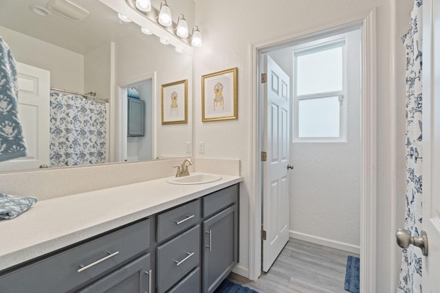 full bathroom with baseboards, vanity, and wood finished floors