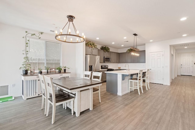 dining area with light wood-type flooring, recessed lighting, and a chandelier