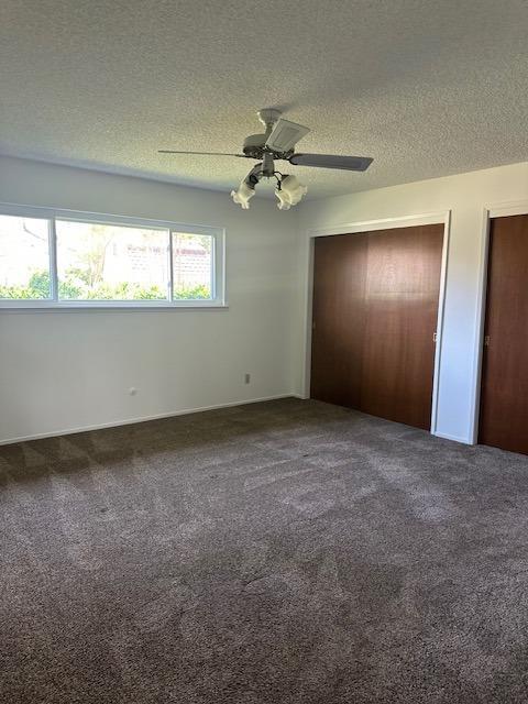 309 Circle Dr, Chowchilla, CA 93610 - unfurnished bedroom with two closets, a ceiling fan, carpet, and a textured ceiling
