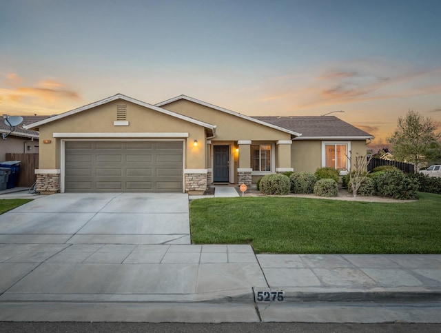 view of front of property featuring a garage, a yard, concrete driveway, and stucco siding