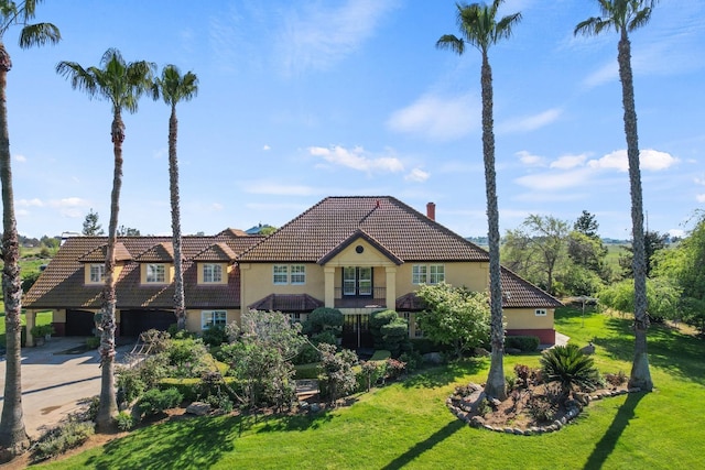 mediterranean / spanish-style home featuring a front yard, concrete driveway, stucco siding, an attached garage, and a tiled roof