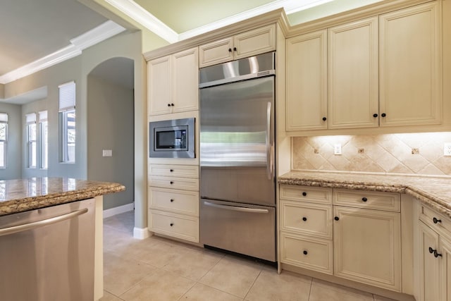 11 W Serena Ave, Clovis, CA 93619 - kitchen featuring built in appliances, cream cabinets, crown molding, tasteful backsplash, and light stone counters