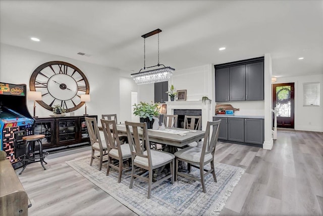 dining space with baseboards, a fireplace, recessed lighting, and light wood finished floors
