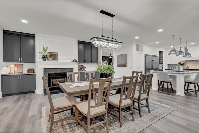 dining area with a fireplace, visible vents, light wood finished floors, and recessed lighting