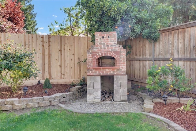 view of patio / terrace with a fenced backyard and an outdoor brick fireplace
