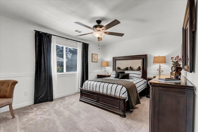 bedroom with visible vents, baseboards, light colored carpet, and ceiling fan