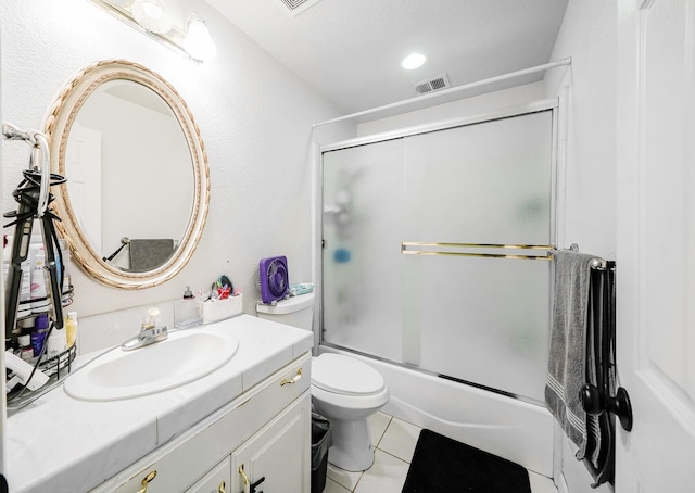 bathroom featuring visible vents, combined bath / shower with glass door, toilet, vanity, and tile patterned flooring