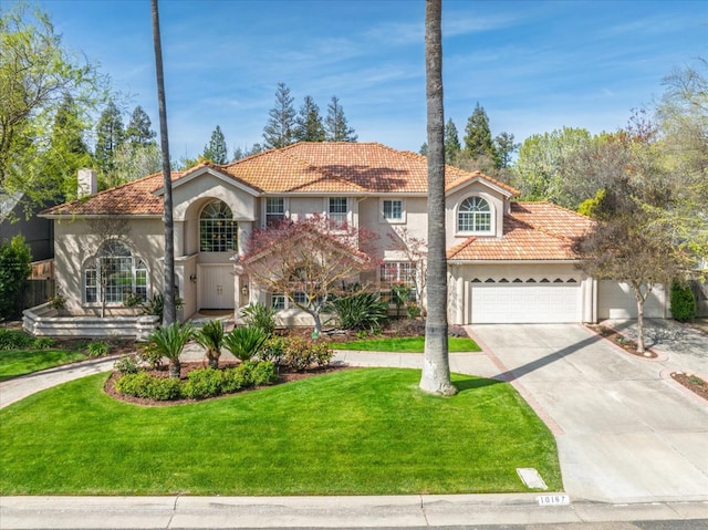 mediterranean / spanish house with a front yard, stucco siding, concrete driveway, an attached garage, and a tile roof