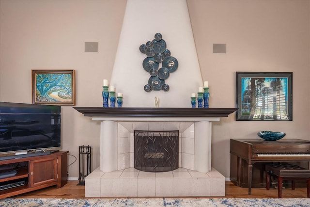 living room with baseboards, visible vents, wood finished floors, and a tile fireplace