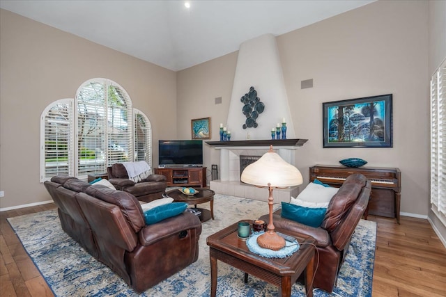 living room featuring baseboards, a towering ceiling, wood finished floors, and visible vents