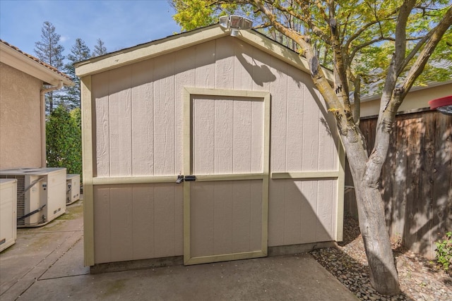 view of shed featuring central air condition unit and fence