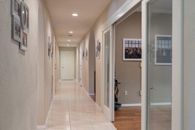 hall with recessed lighting, a textured wall, and baseboards