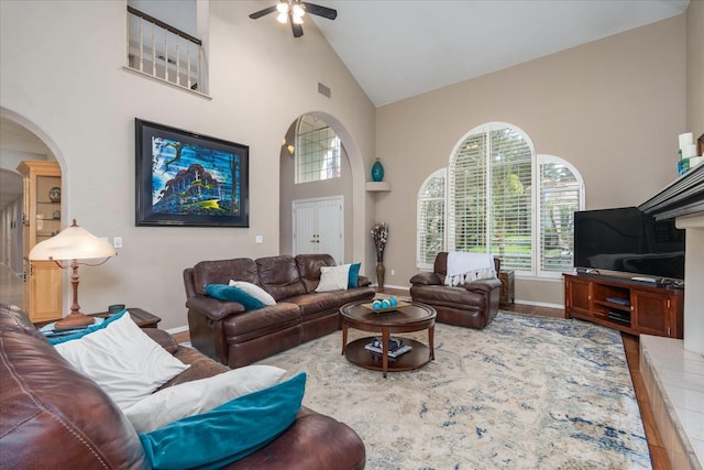 living area featuring plenty of natural light, arched walkways, ceiling fan, and high vaulted ceiling