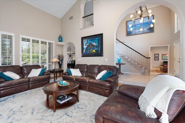 living room featuring stairway, high vaulted ceiling, arched walkways, and a chandelier
