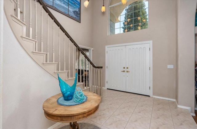 entrance foyer with tile patterned floors, baseboards, a high ceiling, and stairway