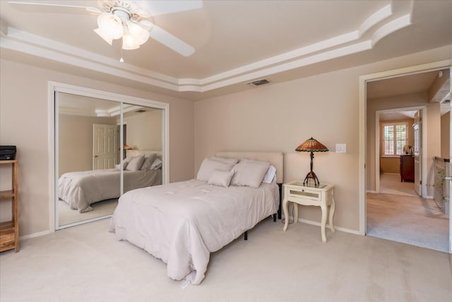 bedroom with a raised ceiling, baseboards, light colored carpet, and visible vents