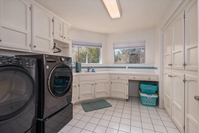 laundry area with cabinet space, separate washer and dryer, a sink, and light tile patterned floors