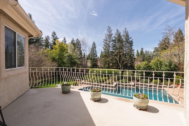 view of patio with a fenced in pool and a balcony