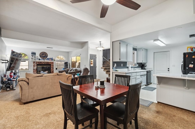 100 Rosewood Cir, Madera, CA 93637 - dining area with a brick fireplace, stairway, light colored carpet, visible vents, and a ceiling fan