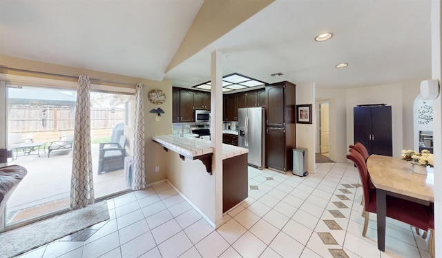7186 N Gregory Ave, Fresno, CA 93722 - kitchen featuring stainless steel appliances, a peninsula, dark brown cabinetry, light tile patterned flooring, and recessed lighting