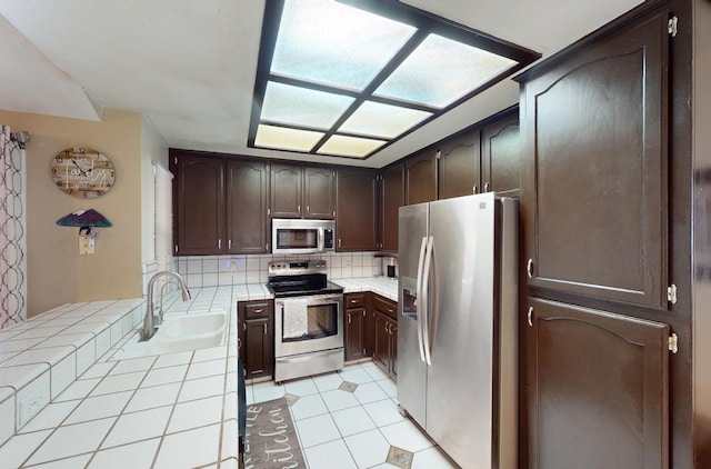 7186 N Gregory Ave, Fresno, CA 93722 - kitchen with appliances with stainless steel finishes, tile countertops, a sink, dark brown cabinetry, and backsplash