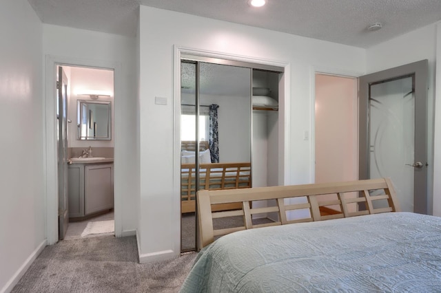 bedroom with carpet, baseboards, a textured ceiling, a sink, and a closet