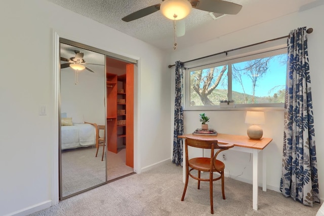 carpeted office space featuring a textured ceiling, baseboards, and ceiling fan