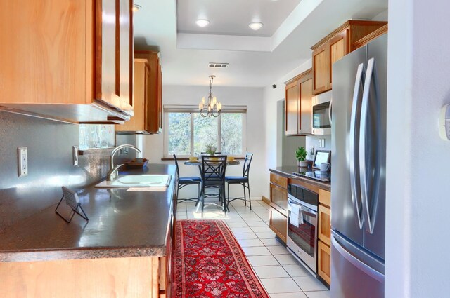 kitchen featuring a sink, a raised ceiling, appliances with stainless steel finishes, visible vents, and dark countertops