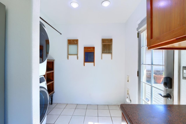 laundry room with stacked washer / dryer, light tile patterned flooring, and cabinet space