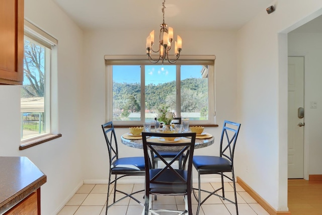 dining area with a wealth of natural light, light tile patterned floors, baseboards, and an inviting chandelier