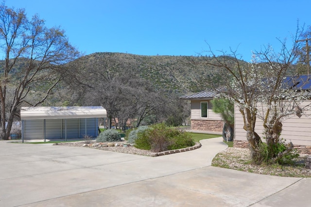 exterior space featuring driveway, metal roof, stone siding, and a mountain view