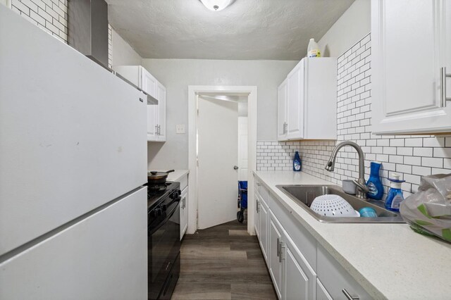 kitchen with black range with gas stovetop, light countertops, a sink, freestanding refrigerator, and white cabinets